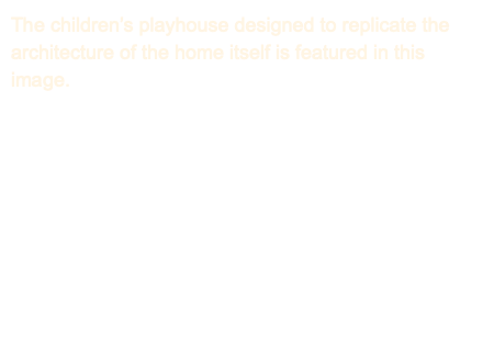 The children’s playhouse designed to replicate the architecture of the home itself is featured in this image. 